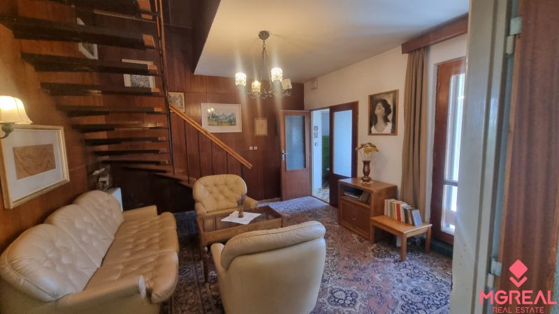 Interior of a family house with a cozy living room, wooden staircase, and light furniture.