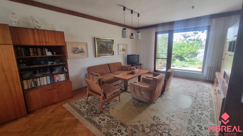 Living room in a family house with a wood-patterned floor and a large window.