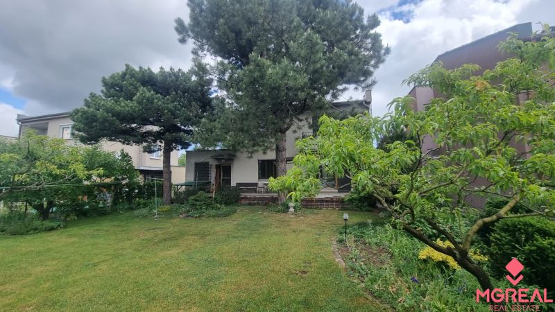 A family house in Leopoldov surrounded by a garden with a lawn and trees.