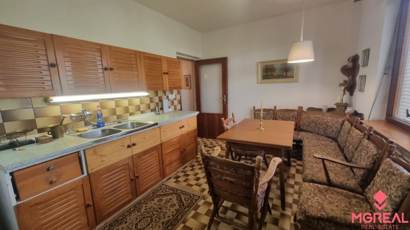A kitchen in a family house with wooden cabinets, a corner sofa, and a dining table.
