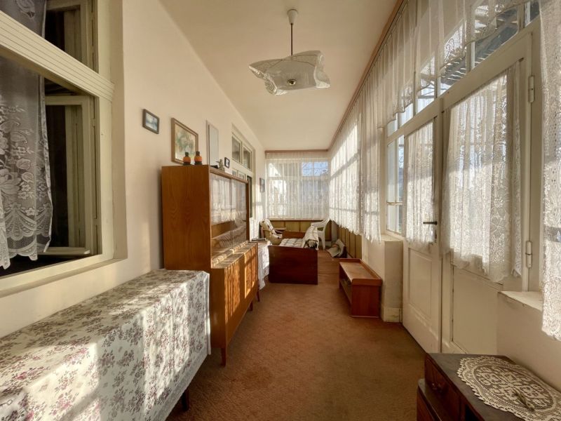 Interior of a sunny winter garden with furniture and decorative curtains in the plot - living.