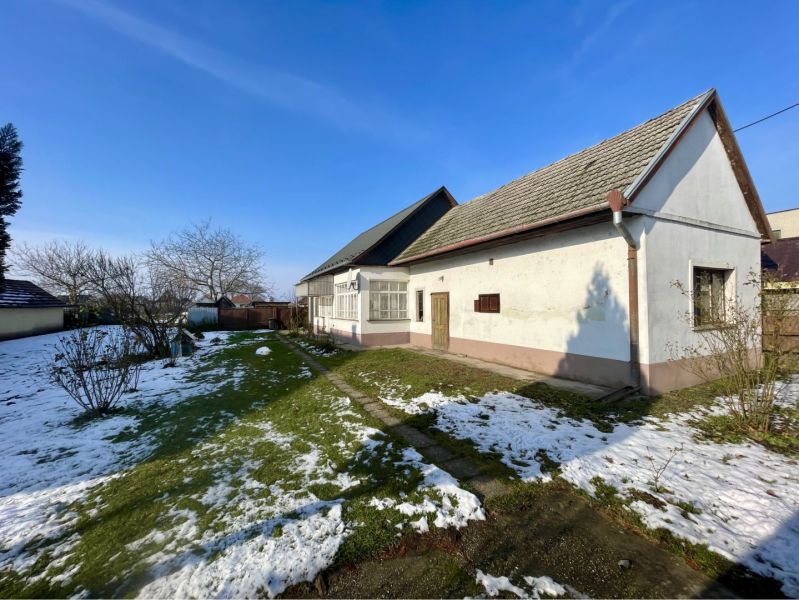 A family house in Vrakúňa surrounded by a garden with a lawn and remnants of snow.