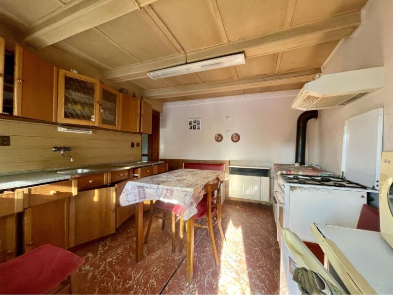 A kitchen with wooden cabinets and a dining table in the plots - living.