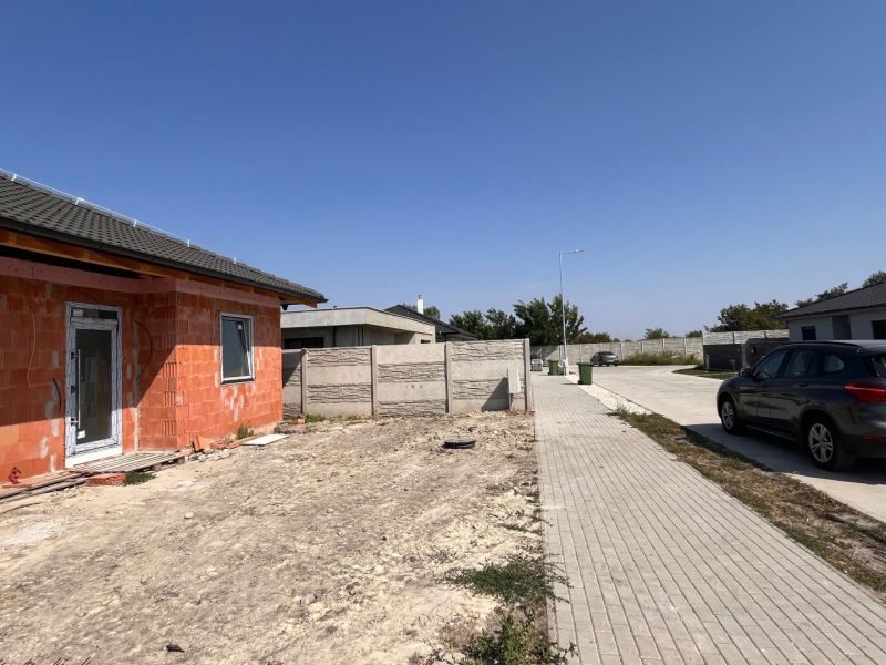 An unfinished family house in Povoda near an unspecified street, next to a paved road and a car.