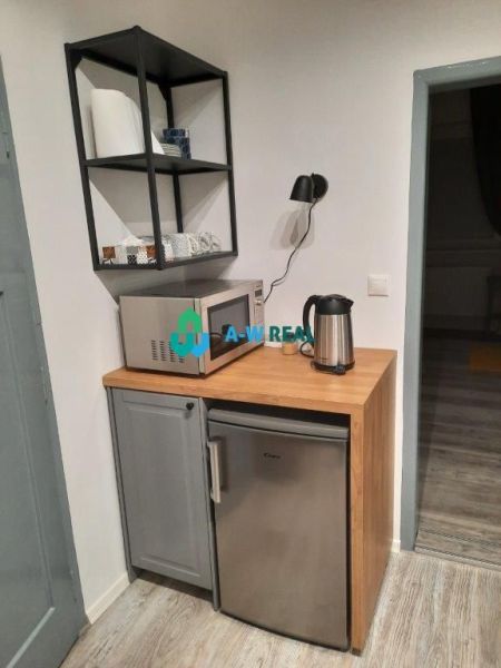 Kitchen corner in a family house with a microwave, refrigerator, and wooden decor flooring.