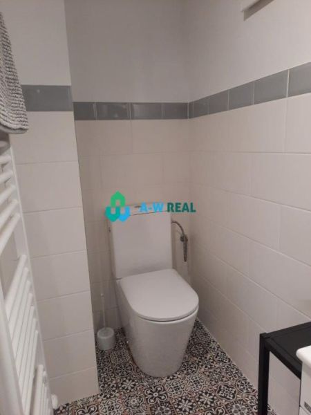 A bathroom in a family house with white tiles and patterned flooring.