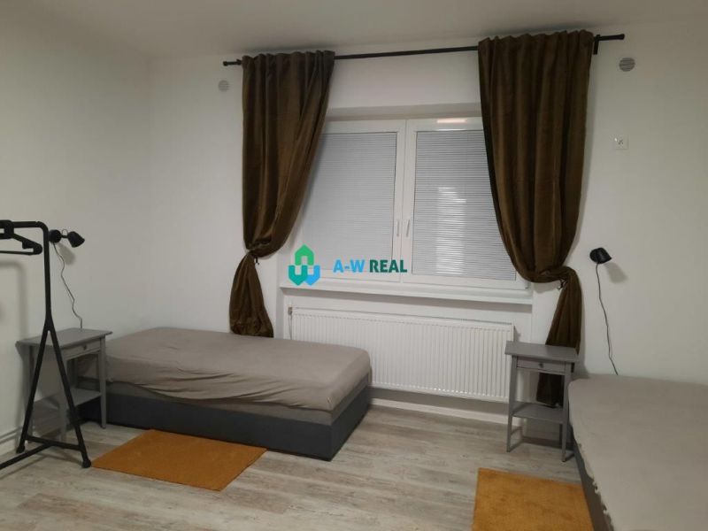 A room in a family house with beds, nightstands, and a floor with a wooden decor.