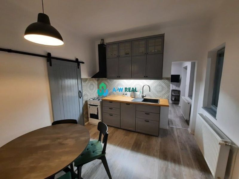 A kitchen with a wooden decor floor in a family house, with gray cabinets and a table.