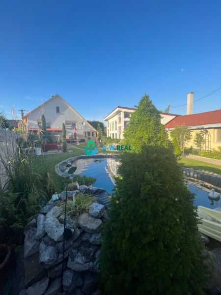The garden of a family house in Orechová Potôň with a pond and a lawn.