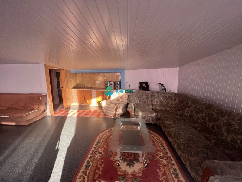Living room with a sofa and a kitchenette in a family house with a wooden decor floor.