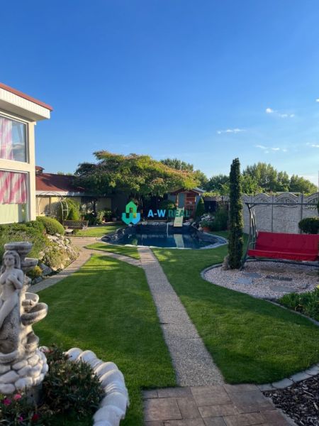 The garden of a family house in Orechová Potôň with a swimming pool, lawns, and a statue.