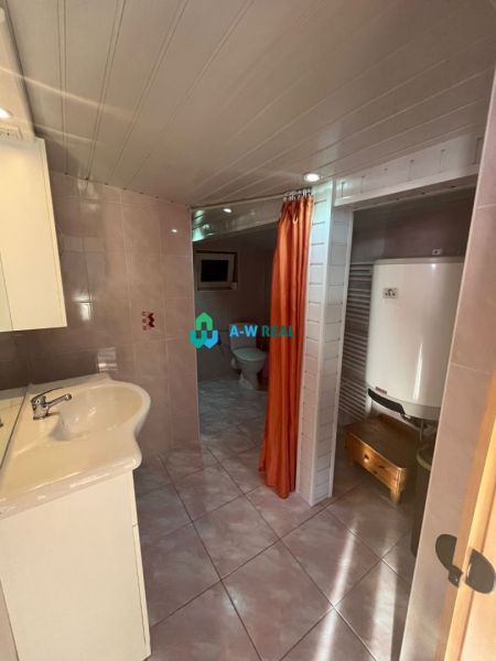A bathroom in a family house with a sink, a heater, and an orange curtain.