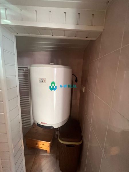 A boiler in the bathroom of a family house, next to the radiator and the basket, with a ceramic floor.