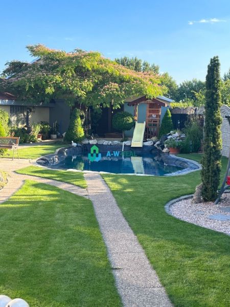A family house in Orechová Potôň with a garden, lawn, swimming pool, and flowers.