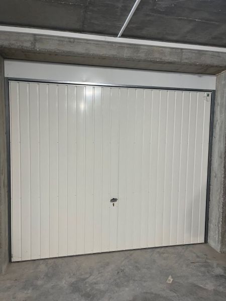 A closed metal garage door in a 3-room apartment with concrete walls.