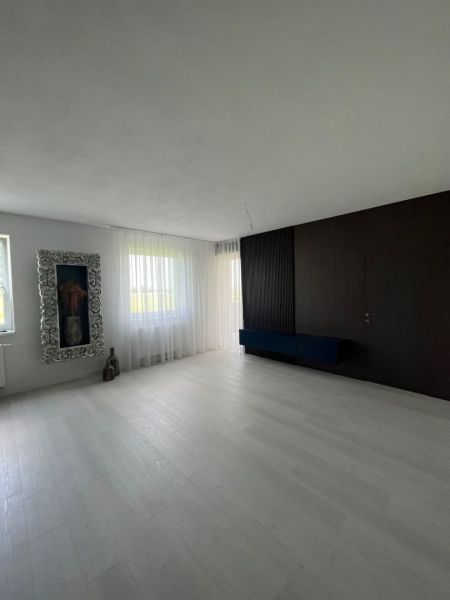 The interior of a spacious room with a white floor and dark walls in a 3-room apartment.