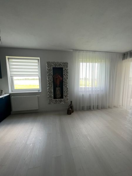 Spacious living room with wood-decor flooring and a decorative frame in a 3-room apartment.