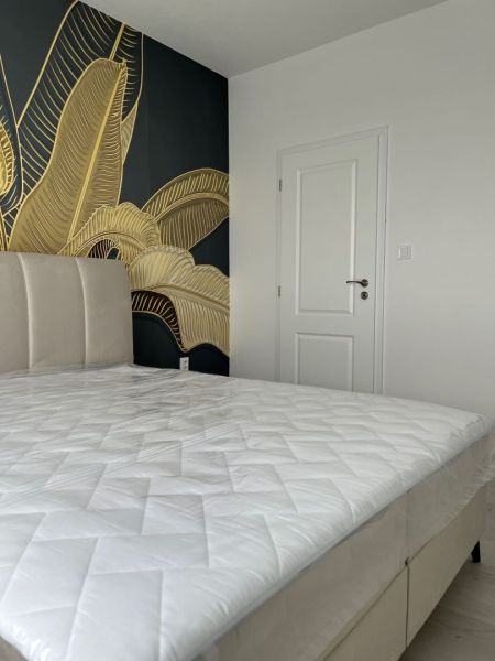 A bedroom in a 3-room apartment with an upholstered bed and golden wallpaper.