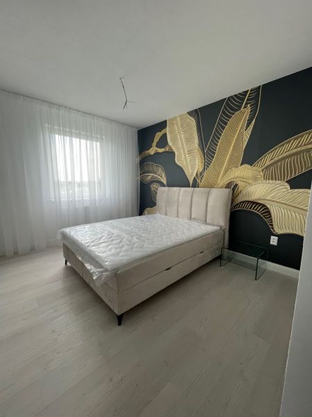 A bedroom in a 3-room apartment with decorative wallpaper and a wooden decor floor.