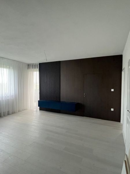 Living room with a dark wall and wood-decorated floor in a 3-room apartment.