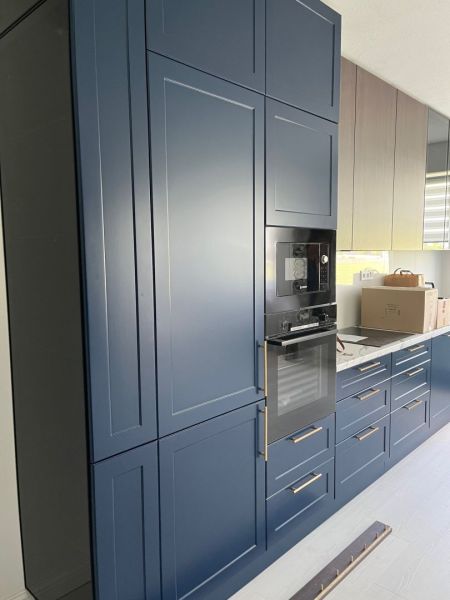 A kitchen in a 3-room apartment with dark blue built-in cabinets and appliances.