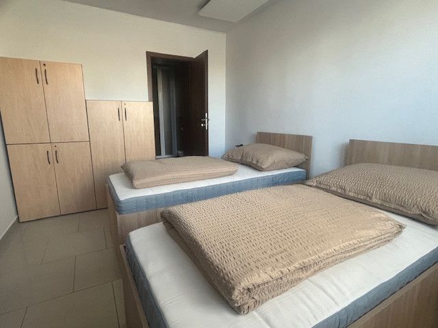 A room in a building with two beds and a wardrobe, a floor with a wooden decor.