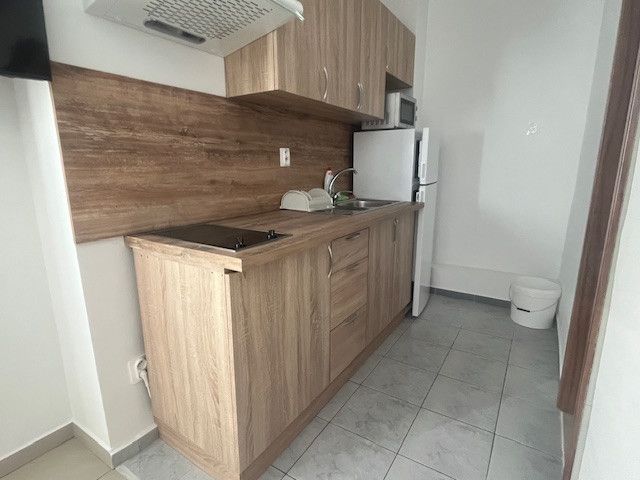 A kitchen with wooden decor, white appliances, a sink, and tiles on the wall.