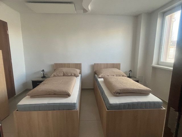 A room with two single beds and nightstands in a building.