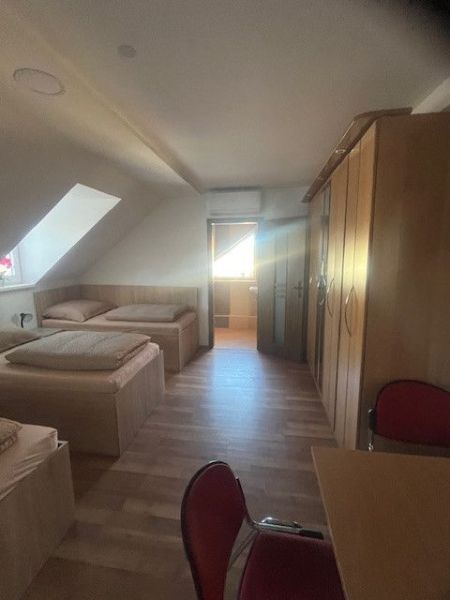 Attic room with single beds, wooden decor flooring, and a built-in wardrobe.