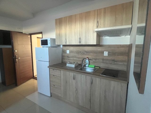 Interior of a kitchen with wood-patterned flooring and kitchen cabinets in a building.
