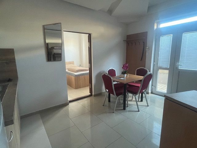 A dining room with a marble floor, a table with chairs, and an entrance to a bedroom in a building.