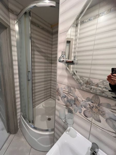 Bathroom with floral tiles and a shower in a studio apartment.