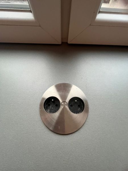 A metal drawer built into the desktop under the window in a studio apartment.