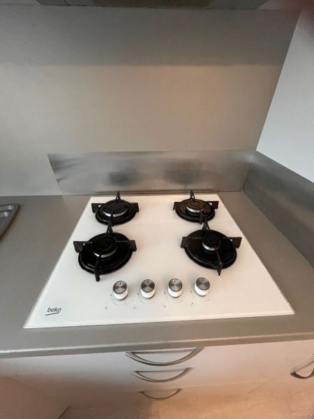 A gas stove with four burners and stainless steel control knobs in a studio apartment.