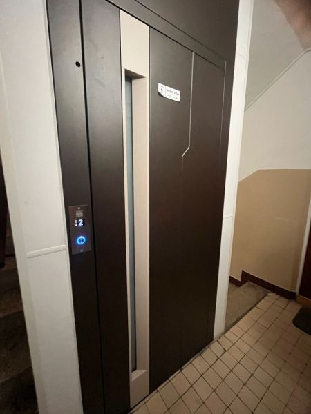 There is a brown elevator with a digital panel in the apartment building.