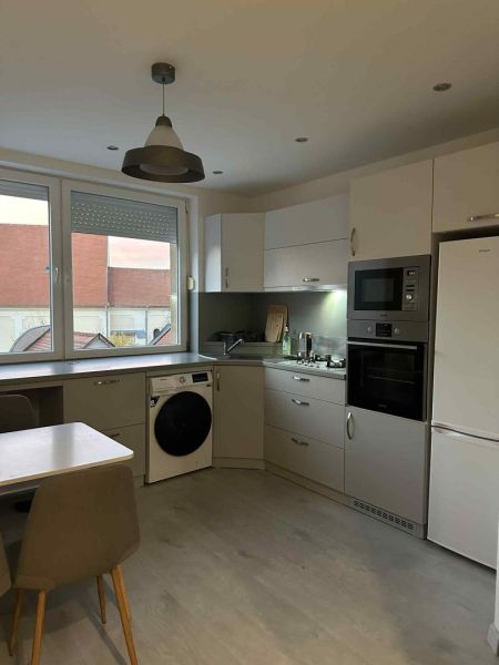 A kitchen with a dining table, built-in appliances, and a wooden decor floor in a studio apartment.