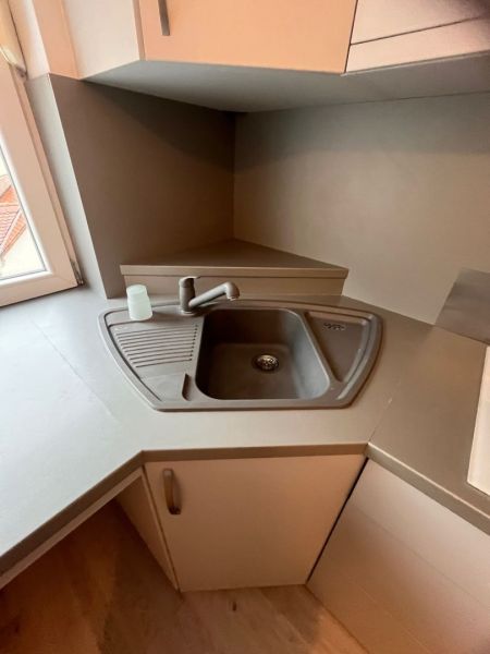 Kitchen area with a corner sink and faucet in a studio apartment.