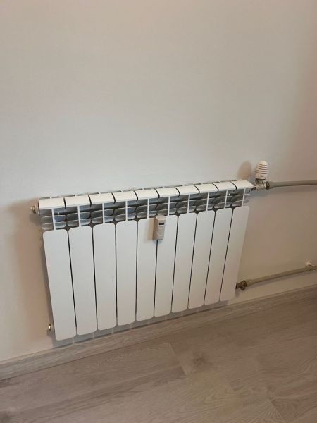 Radiator on the wall with a wooden decor floor in a studio apartment.