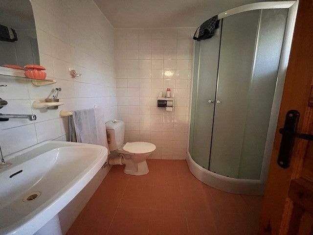 A bathroom in a family house with a bathtub, shower, and white tiles.