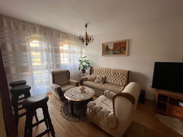 Living room in a family house with a wooden decor floor, a couch, and a television.