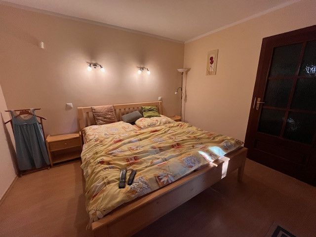 A bedroom in a family house with a large bed and a floor with a wooden decor.