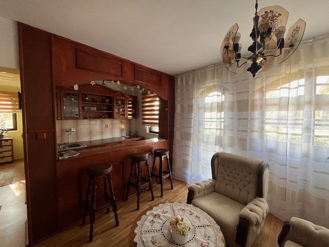The interior of a family house with a bar counter, wooden decor flooring, and comfortable armchairs.