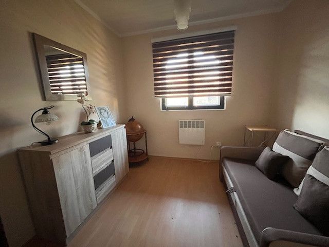 A room in a family house with a wooden decor floor and a darkened window.