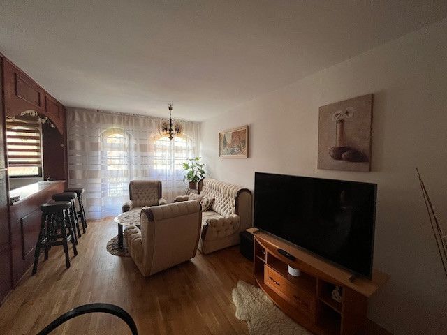 Living room of a family house with a wooden decor floor, a sofa, and a television.