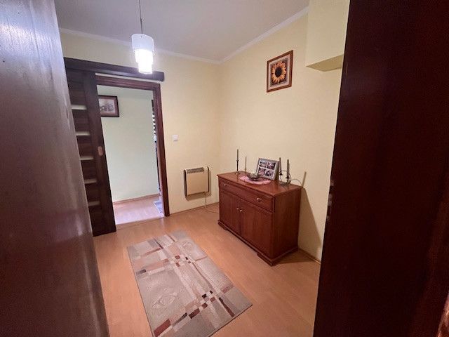 A hallway with carpet, wooden decor, a cabinet, and decoration in a family house.