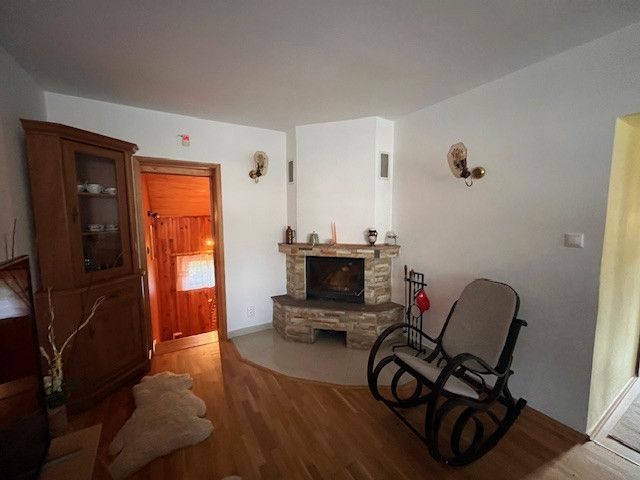 A room in a family house with a fireplace, a rocking chair, and a floor with a wooden decor.