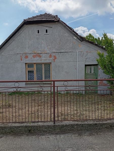 A family house in Ňárad with an old facade, a fence, and closed windows.