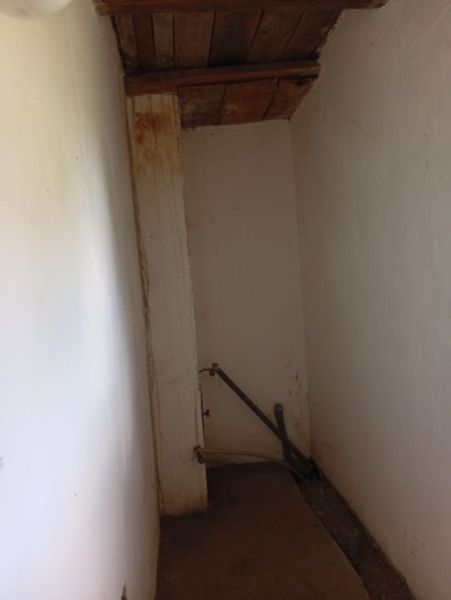 A narrow space in a family house with thick white walls and a wooden ceiling.
