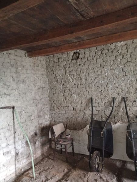 Interior of a family house with brick walls, a chair, and two wheelbarrows.