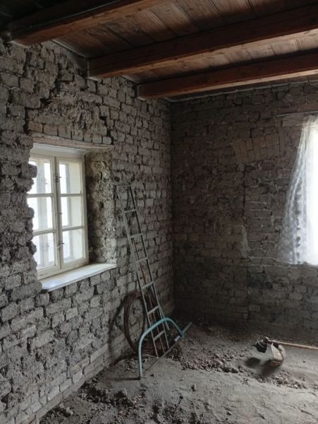 Stone wall, light blue ladder, and a window with a white curtain in a family house.